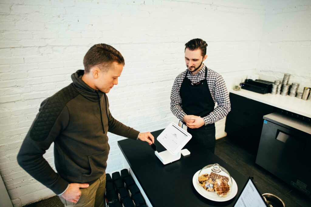 A waiter wearing a polo shirt is taking orders for customers